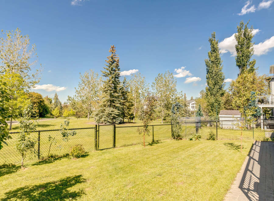 Enjoy the outdoors in this beautifully maintained backyard, complete with a lush green lawn and mature trees providing ample shade.
