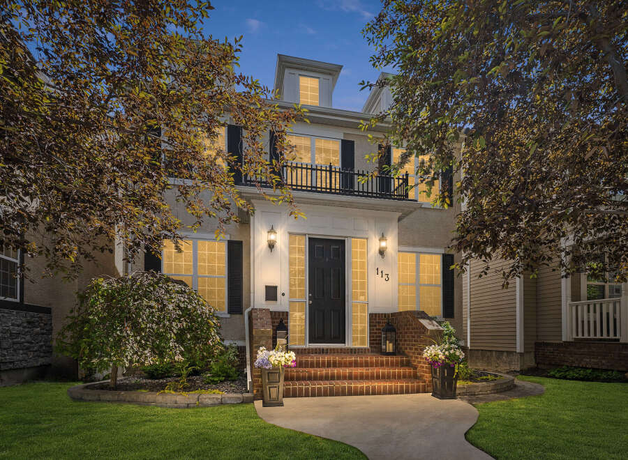 This stunning home features a grand entrance with a paved walkway leading to brick steps and a welcoming front door.