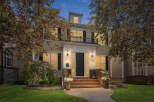 This stunning home features a grand entrance with a paved walkway leading to brick steps and a welcoming front door.