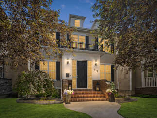 This stunning home features a grand entrance with a paved walkway leading to brick steps and a welcoming front door.