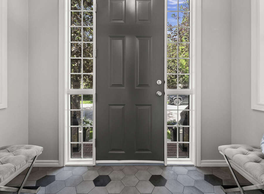 Step into this welcoming entryway featuring a stylish dark gray front door flanked by tall, multi-paned windows that allow natural light to flood the space.