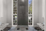 Step into this welcoming entryway featuring a stylish dark gray front door flanked by tall, multi-paned windows that allow natural light to flood the space.