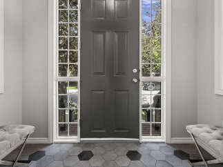 Step into this welcoming entryway featuring a stylish dark gray front door flanked by tall, multi-paned windows that allow natural light to flood the space.