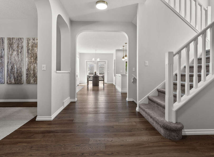 Step into this inviting entryway featuring elegant arched doorways and a grand staircase with plush carpeting.