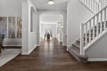 Step into this inviting entryway featuring elegant arched doorways and a grand staircase with plush carpeting.