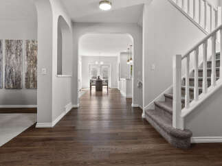 Step into this inviting entryway featuring elegant arched doorways and a grand staircase with plush carpeting.