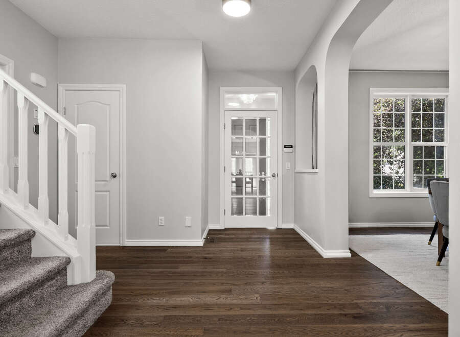 Step into this inviting entryway featuring a grand staircase with plush carpeting and a white banister.