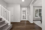Step into this inviting entryway featuring a grand staircase with plush carpeting and a white banister.