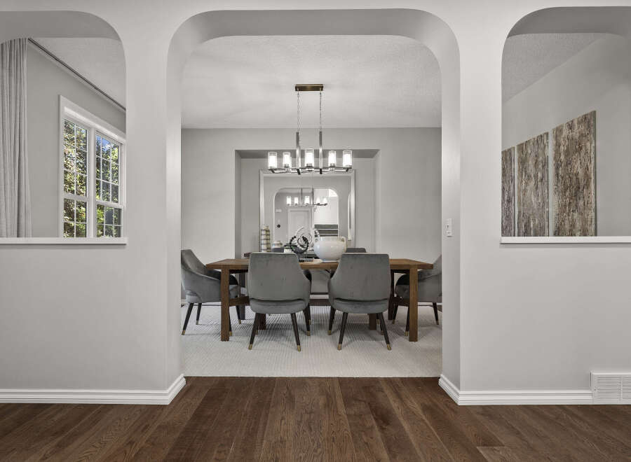 Step into this elegant dining room, featuring a sleek wooden table surrounded by plush velvet chairs.