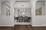 Step into this elegant dining room, featuring a sleek wooden table surrounded by plush velvet chairs.