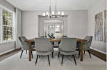 This elegant dining room features a modern rectangular chandelier illuminating a sturdy wooden dining table surrounded by plush grey velvet chairs.