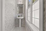 This powder room features elegant leaf-patterned wallpaper and a sleek pedestal sink.