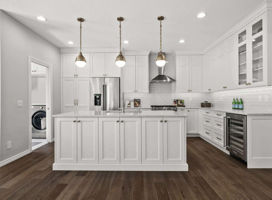 Experience luxury in this stunning white kitchen, featuring a spacious island with ample cabinet storage and elegant marble countertops.