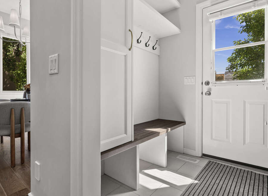 Step into this inviting entryway, featuring a built-in bench with ample storage and a convenient coat rack.