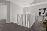 Step into this beautifully appointed hallway featuring plush grey carpeting and elegant white railings.