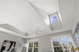 Experience luxury living with this stunning bedroom featuring a dramatic coffered ceiling and a modern ceiling fan.