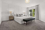 Experience luxurious comfort in this master bedroom, featuring elegant board and batten wall detailing and a plush upholstered bed.