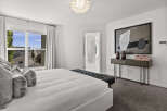 Experience luxury in this master bedroom, featuring a king-sized bed adorned with plush pillows and a stylish tufted bench at the foot.
