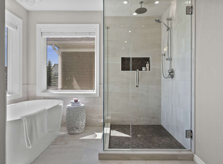 Experience luxury in this stunning bathroom, featuring a freestanding soaking tub and a spacious glass-enclosed shower with a rainfall showerhead.