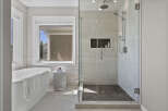 Experience luxury in this stunning bathroom, featuring a freestanding soaking tub and a spacious glass-enclosed shower with a rainfall showerhead.