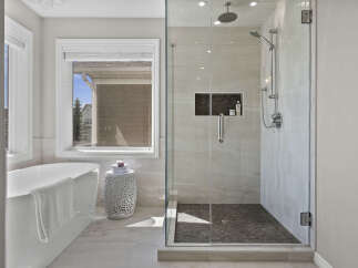 Experience luxury in this stunning bathroom, featuring a freestanding soaking tub and a spacious glass-enclosed shower with a rainfall showerhead.