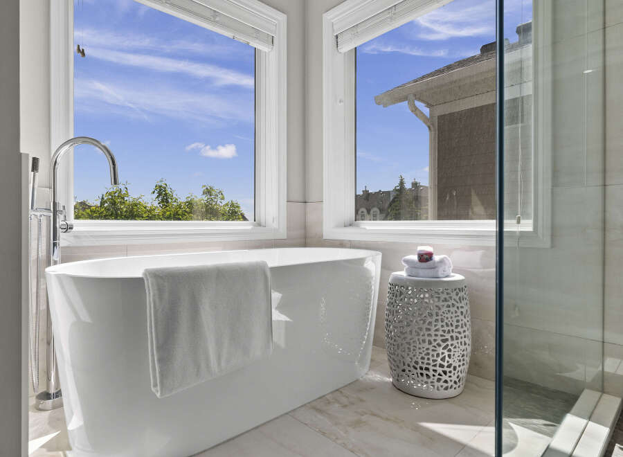 Indulge in luxury with this stunning freestanding bathtub, perfectly positioned to offer breathtaking views of the serene outdoors through expansive windows.