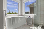 Indulge in luxury with this stunning freestanding bathtub, perfectly positioned to offer breathtaking views of the serene outdoors through expansive windows.
