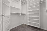 Step into this spacious walk-in closet, featuring ample white shelving and built-in drawers for organized storage.
