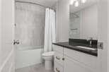 This modern bathroom features a sleek vanity with a dark countertop and brass hardware, complemented by a stylish faucet.