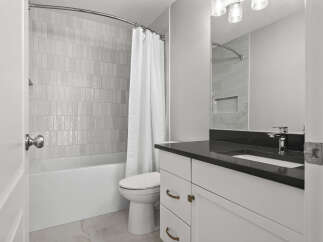 This modern bathroom features a sleek vanity with a dark countertop and brass hardware, complemented by a stylish faucet.