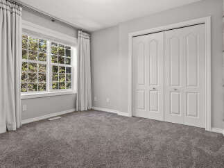 This bedroom features a large window with abundant natural light, complemented by elegant grey curtains.