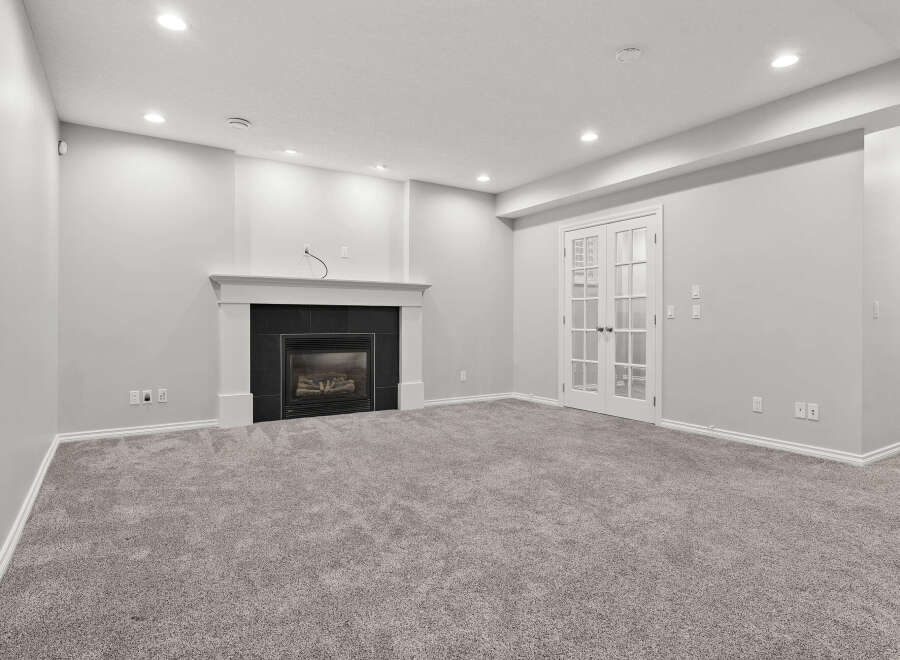 This spacious basement living area features a modern gas fireplace with a sleek black tile surround, perfect for cozy evenings.