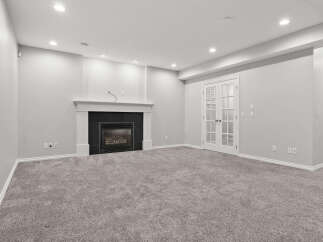 This spacious basement living area features a modern gas fireplace with a sleek black tile surround, perfect for cozy evenings.