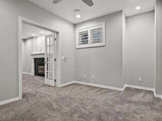 Step into this inviting living space featuring a cozy fireplace and elegant French doors that open to a well-appointed room.