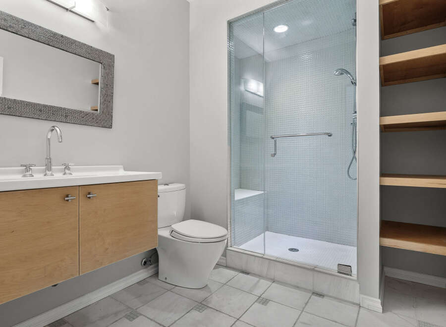 This modern bathroom features a sleek vanity with a chrome faucet and a large, textured mirror.