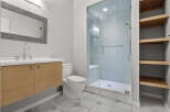 This modern bathroom features a sleek vanity with a chrome faucet and a large, textured mirror.