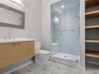 This modern bathroom features a sleek vanity with a chrome faucet and a large, textured mirror.