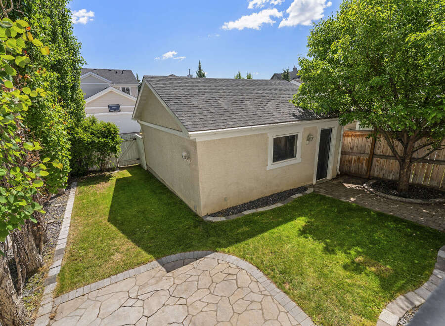 Discover this charming backyard oasis featuring a detached garage and a lush green lawn perfect for outdoor activities.