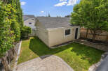 Discover this charming backyard oasis featuring a detached garage and a lush green lawn perfect for outdoor activities.