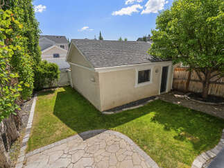 Discover this charming backyard oasis featuring a detached garage and a lush green lawn perfect for outdoor activities.