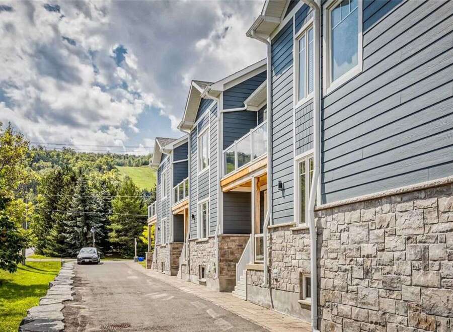 Discover modern living in this stunning townhouse complex, featuring sleek blue siding and elegant stone accents.