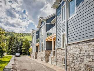 Discover modern living in this stunning townhouse complex, featuring sleek blue siding and elegant stone accents.