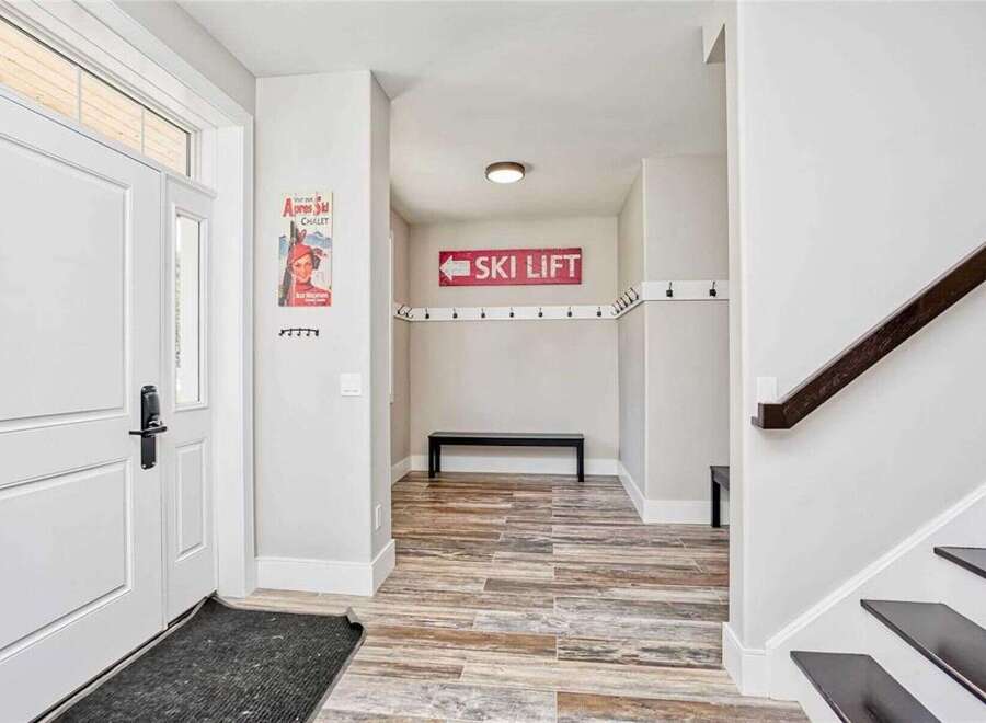 Step into this welcoming entryway featuring a stylish ski lift sign and ample coat hooks, perfect for a mountain retreat.