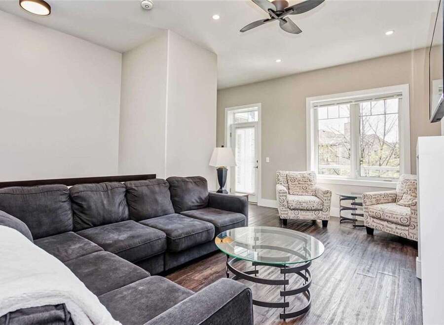 Experience modern living in this spacious living room, featuring a comfortable sectional sofa and two accent chairs adorned with a unique script pattern.