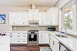 This stunning kitchen boasts sleek white cabinetry and a modern stainless steel gas range, perfect for any home chef.