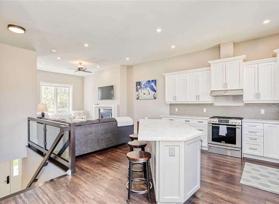 Experience modern living in this open-concept home featuring a spacious kitchen with white cabinetry and a sleek backsplash, perfect for entertaining.