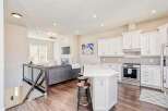 Experience modern living in this open-concept home featuring a spacious kitchen with white cabinetry and a sleek backsplash, perfect for entertaining.