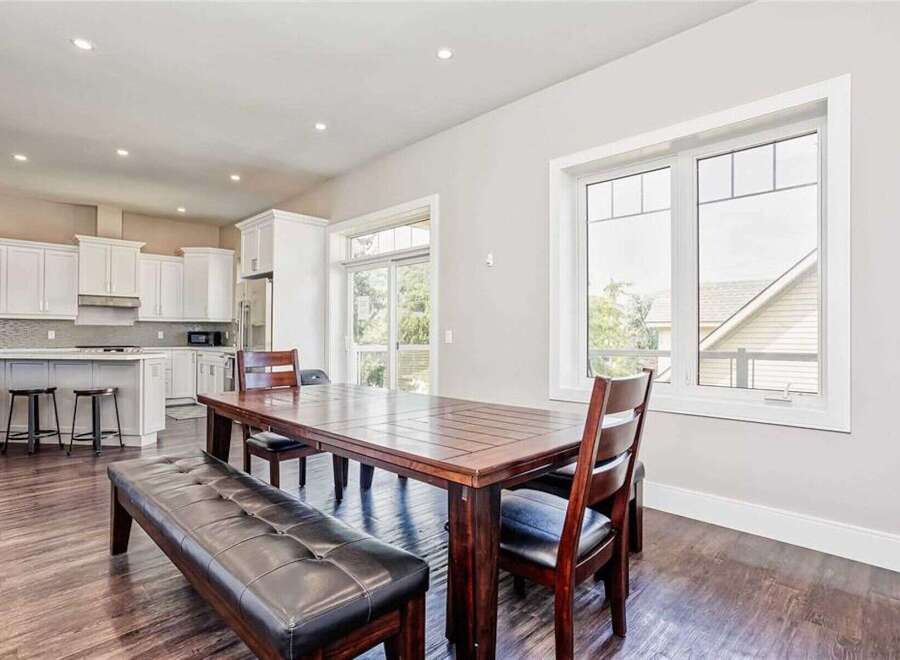 This spacious open-concept dining and kitchen area features a large wooden dining table with a leather bench and chairs, perfect for family gatherings.