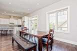 This spacious open-concept dining and kitchen area features a large wooden dining table with a leather bench and chairs, perfect for family gatherings.