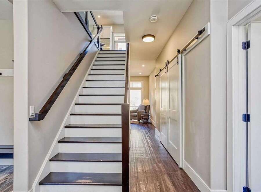 This modern home features a striking staircase with dark wood treads and white risers, complemented by a sleek glass and dark wood railing.